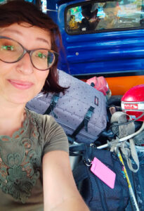 Elena sorridente ma preoccupata, sul retro di un camioncino traballante.